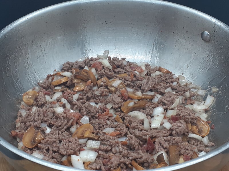 skillet of browned ground beef, diced onions, bacon bits and mushrooms