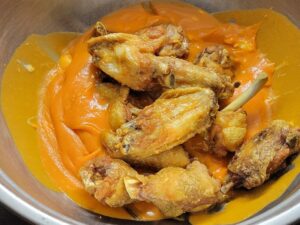 Hot Fried Chicken Wings into the bowl of Buffalo Sauce