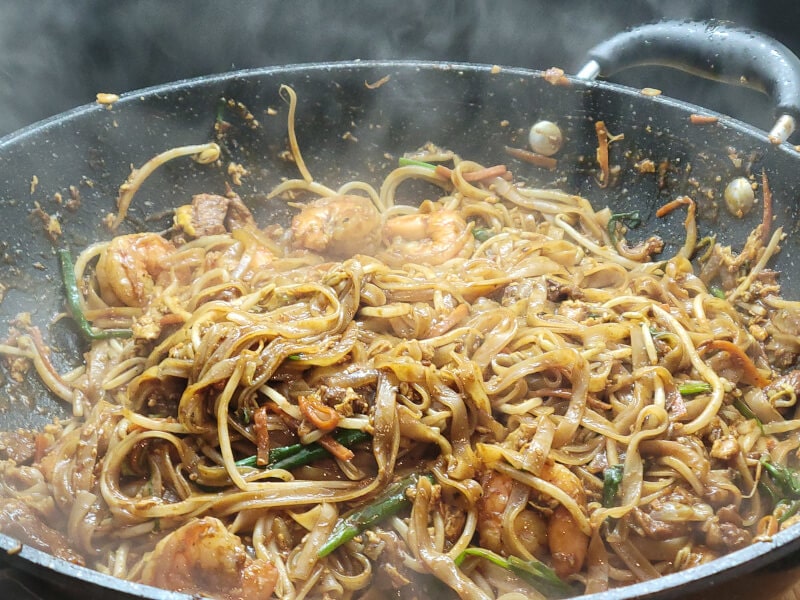 Wok Peanut Pad Thai adding bean sprouts, green onions and shrimp to cook the last 2-3 minutes